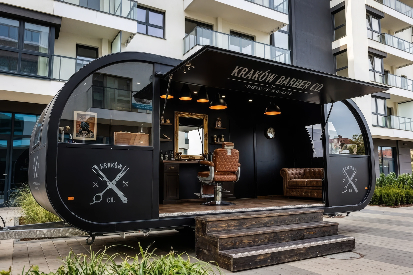 Mobilna przyczepa usługowa- barber Czarna nowoczesna przyczepa znajduje się na tle bloków mieszkalnych. W środku przyczepy znajduje się barber.