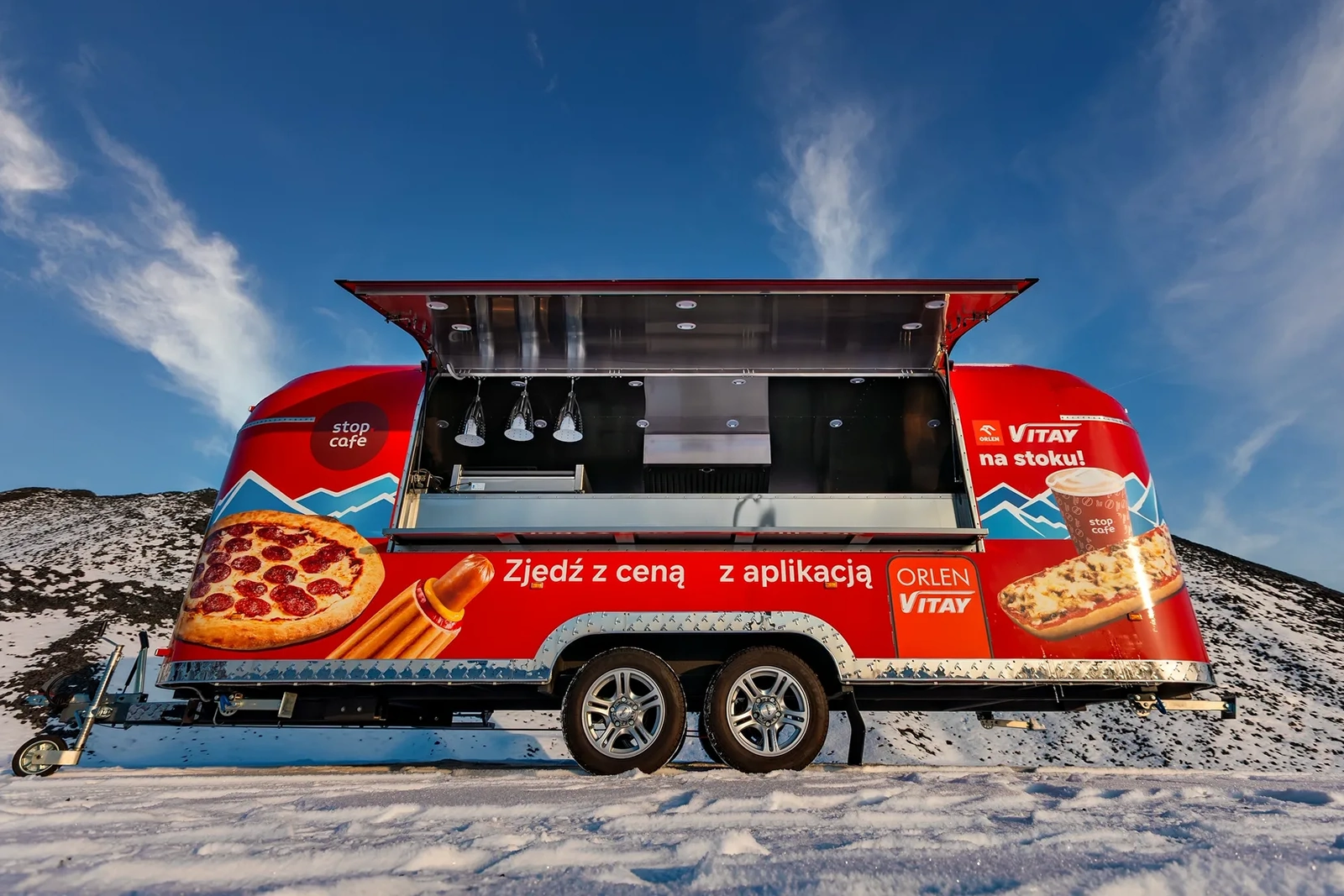 Červený reklamný príves SHINE s kompletným brandingom pre značky ORLEN a Stop Cafe. Luxusný promo príves pripravený na zimnú kampaň v prostredí zasnežených svahov.